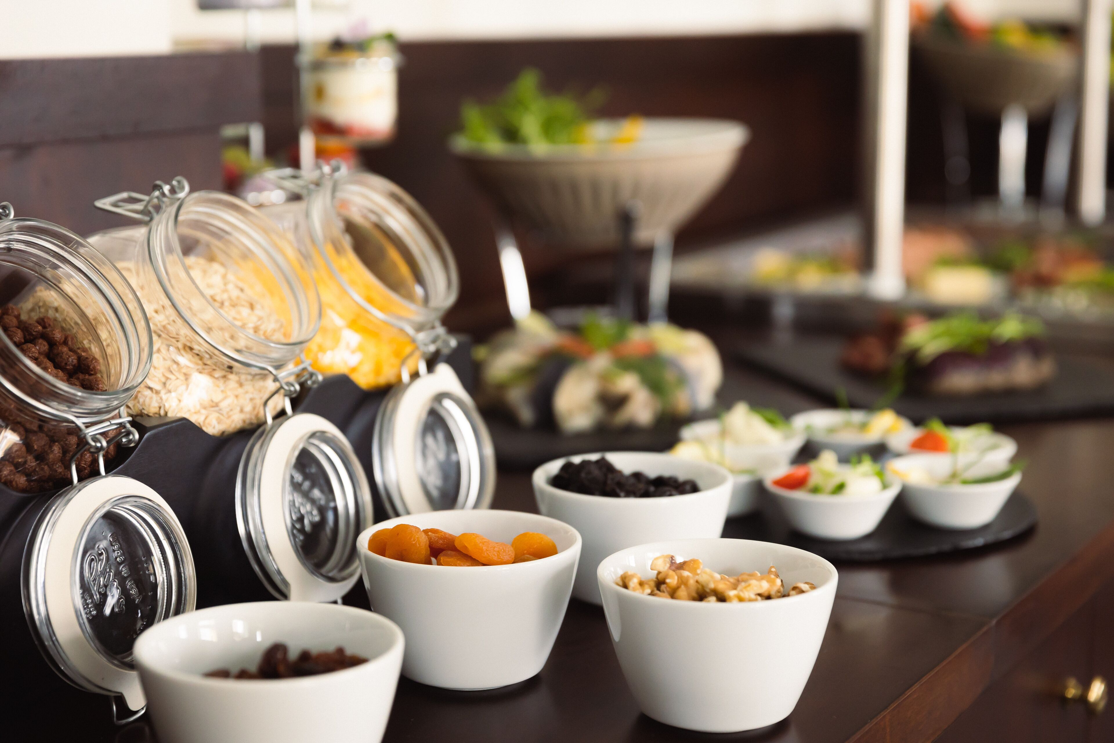Un buffet proposant une variété d’aliments, notamment des bols remplis de noix, de fruits secs et de céréales.