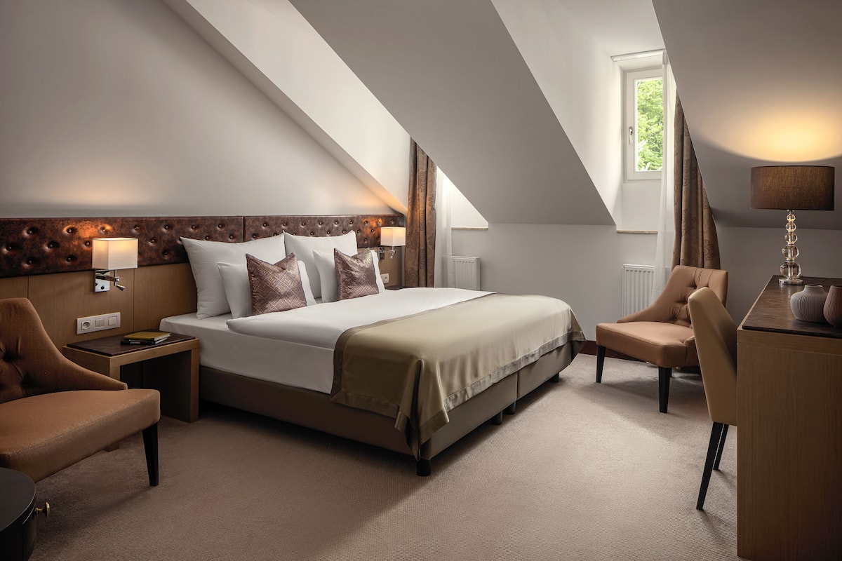 Una habitación de hotel moderna con una cama grande, un escritorio y una silla.