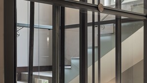 Een modern interieur met een glazen balustrade, een trap en uitzicht op een kamer met een lamp.