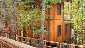 A wooden cabin with a balcony, surrounded by trees.