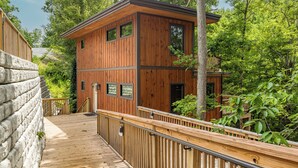 Une cabane en bois dotée d’une terrasse, entourée d’arbres.