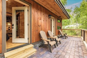 Una cabaña de madera con un porche, dos sillas Adirondack y una terraza de madera.