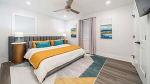 A bedroom with a bed, a ceiling fan, a TV, and artwork on the walls. - Lakefront Elegance | Boat Launch | Hot Tub | Dock (Hot Springs)
