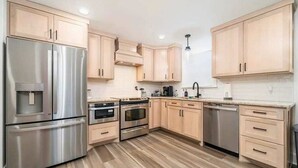 A modern kitchen with stainless steel appliances, wooden cabinets, and a tiled backsplash. - Lakefront Elegance | Boat Launch | Hot Tub | Dock (Hot Springs)