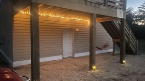 A wooden deck with string lights, a door, and a hammock. - Luxury Golf Villa w/ Hot Tub  Stunning Golf Course Views Near OBX Beaches (Kitty Hawk)