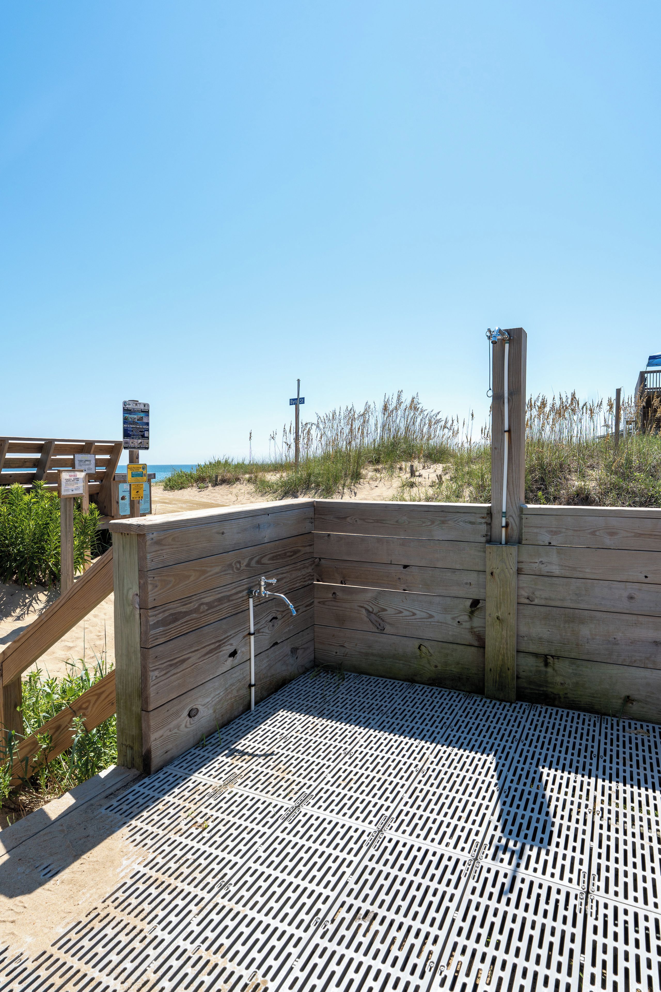 A wooden structure with a metal grate floor, a wooden bench, and a signpost with information.