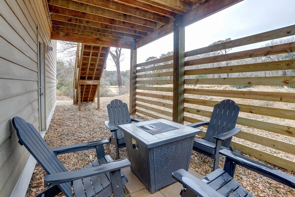 An outdoor patio with a table and four Adirondack chairs, a wooden pergola overhead, and a view of a fenced area with trees. - Luxury Golf Villa w/ Hot Tub Stunning Golf Course Views Near OBX Beaches (Kitty Hawk)