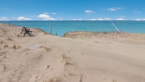 A sandy beach with a metal bench and a white pole. - Griners Life Saving$ Station on Lake Michigan w/ Private Beach, Pet-Friendly (Frankfort)