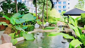Un jardin intérieur paisible, avec un bassin, entouré de rochers et d’une végétation luxuriante.
