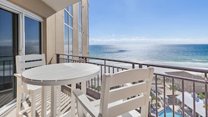 A balcony with a white table and chairs, overlooking a beach and ocean. - Beachfront Gulf Sunset Views ~ Tram Included (Miramar Beach)