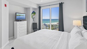 A hotel room with a bed, a TV, a desk, and a view of the ocean. - Beachfront Gulf Sunset Views ~ Tram Included (Miramar Beach)