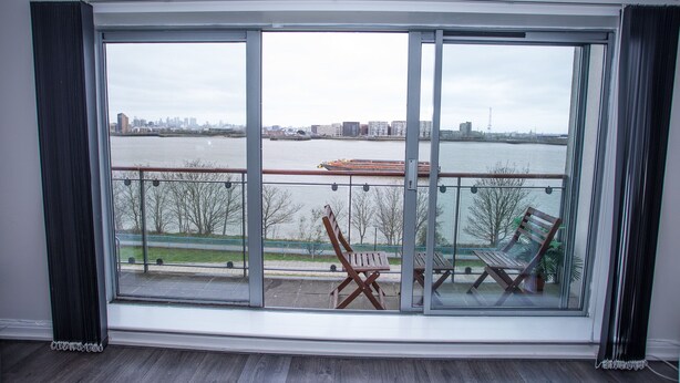 A large window with a view of a river and city skyline. - Remarkable 2-bed Apartment With Sea View (London)