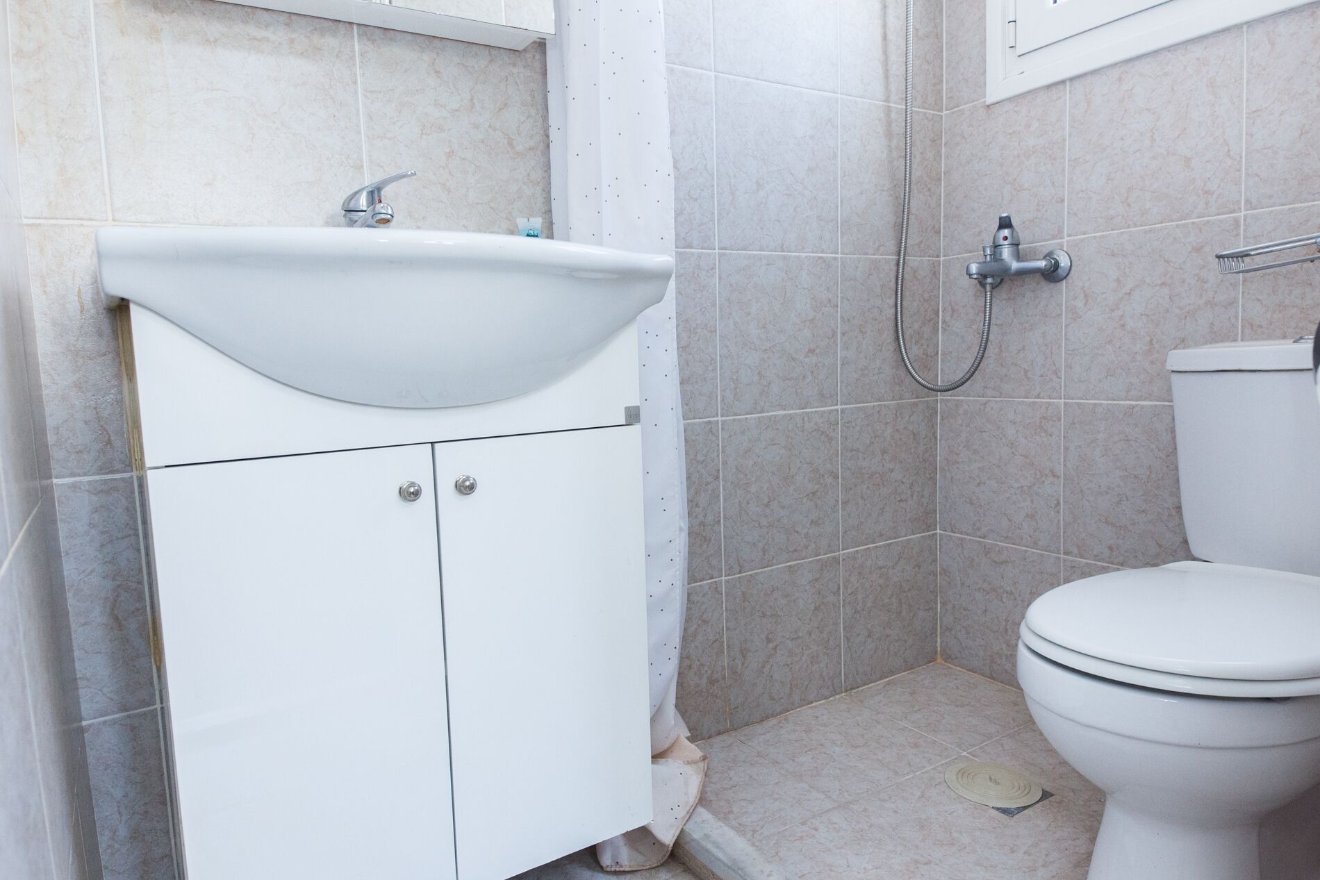 Ein Badezimmer mit weißem Waschbecken, WC und Dusche.