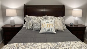 A neatly made bed with patterned bedding, two bedside tables with lamps, and decorative pillows. - Beautifully Decorated Condo with Pool and Fitness Center! Pet Friendly! (Saint Simons Island)