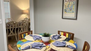 A round dining table with colorful placemats and woven placemats with folded napkins. A potted plant is in the center. - Beautifully Decorated Condo with Pool and Fitness Center! Pet Friendly! (Saint Simons Island)