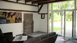 Una habitación con techo de madera, pared de ladrillo, un ventanal grande y un sofá marrón.