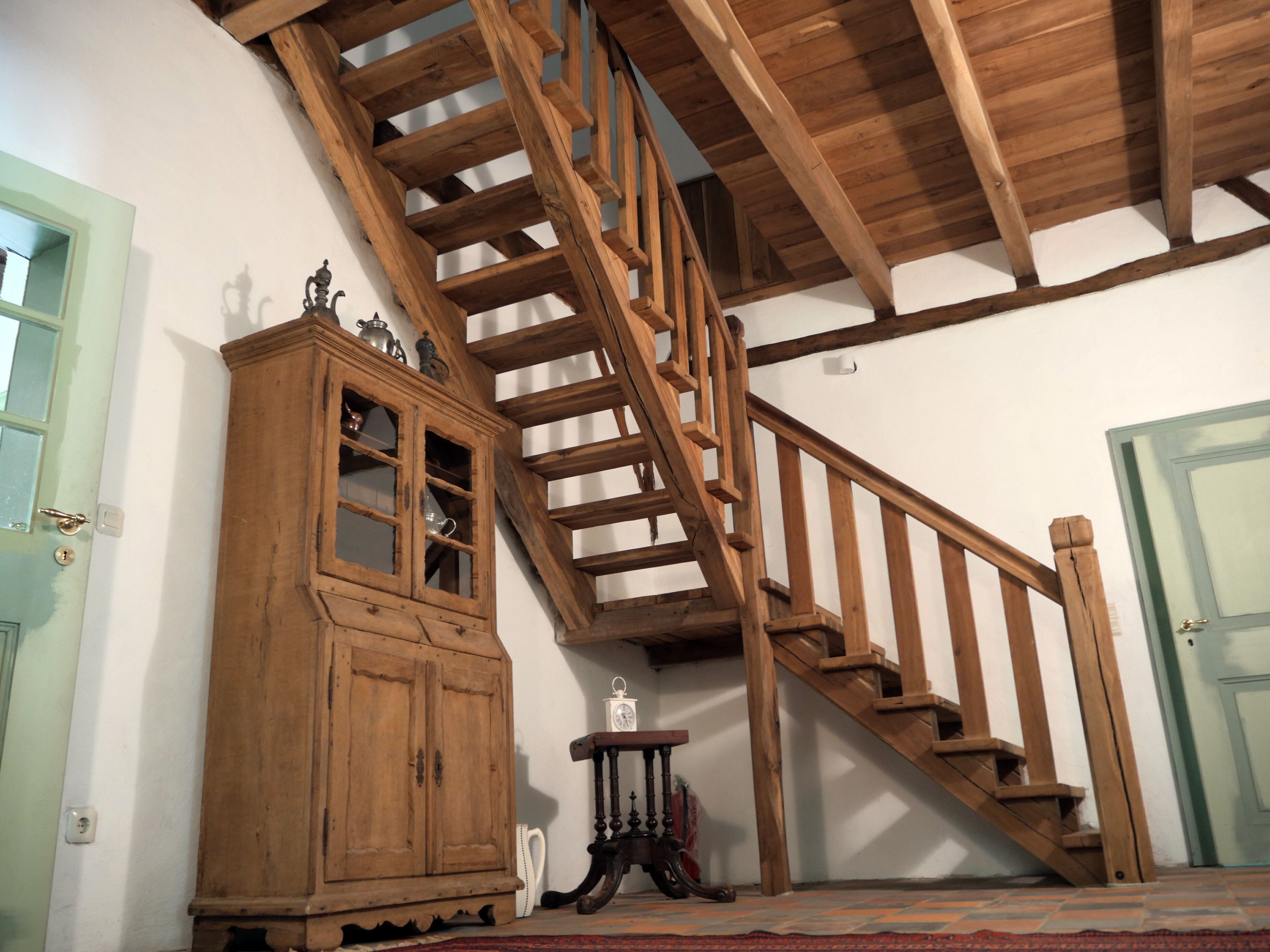 Een houten trap met een houten kast en een klein tafeltje in een kamer met witte muren.