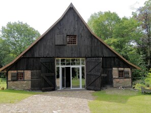 Ein rustikaler Schuppen mit Steinunterbau, großen Holztüren und einem steilen Satteldach.