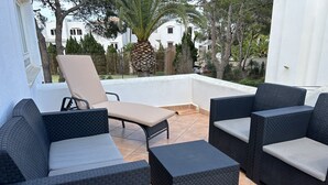 A patio with wicker furniture, including a sofa and chairs, and a small table. - Villa with sea view and pool in Cala D' Or (Santanyí)