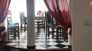 A dining area with checkered flooring, wooden chairs with blue cushions, and red curtains. - Villa with sea view and pool in Cala D' Or (Santanyí)