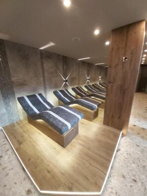A row of massage chairs with a wooden floor and a concrete wall in the background. - Luxury Apartments St Ivan Rilski SPA 4 (Bansko)