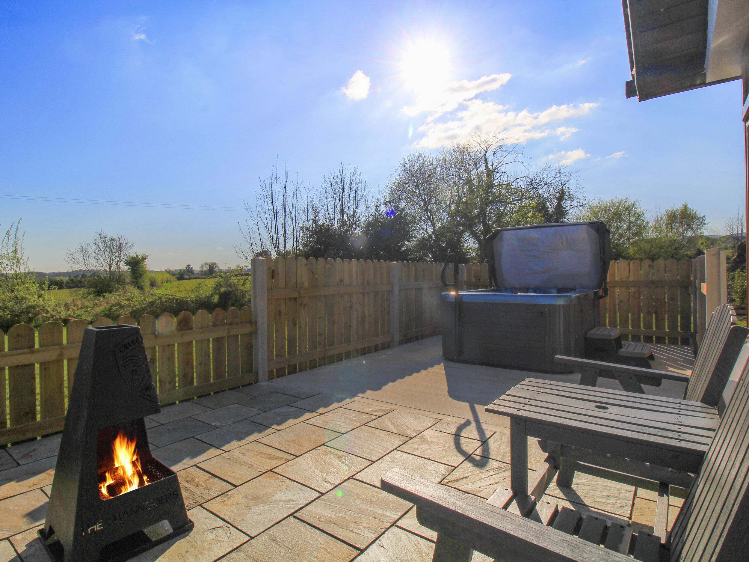 Un espace extérieur aménagé en terrasse, avec un barbecue, des sièges et une vue sur la campagne.