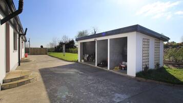 A garage with a covered area, a concrete driveway, and a lawn.