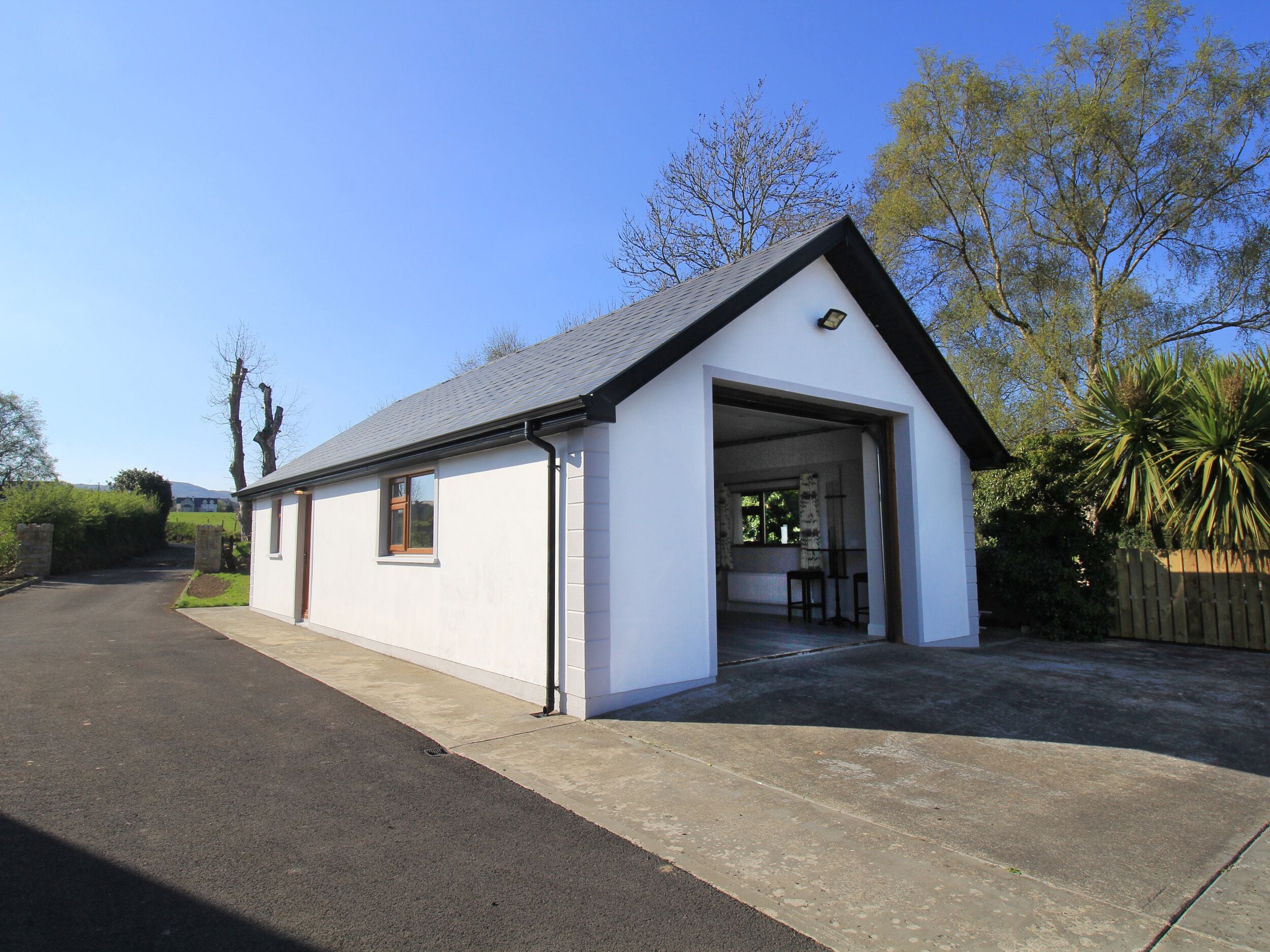 A single-story building with a garage door open, revealing a small interior space with a table and chairs.