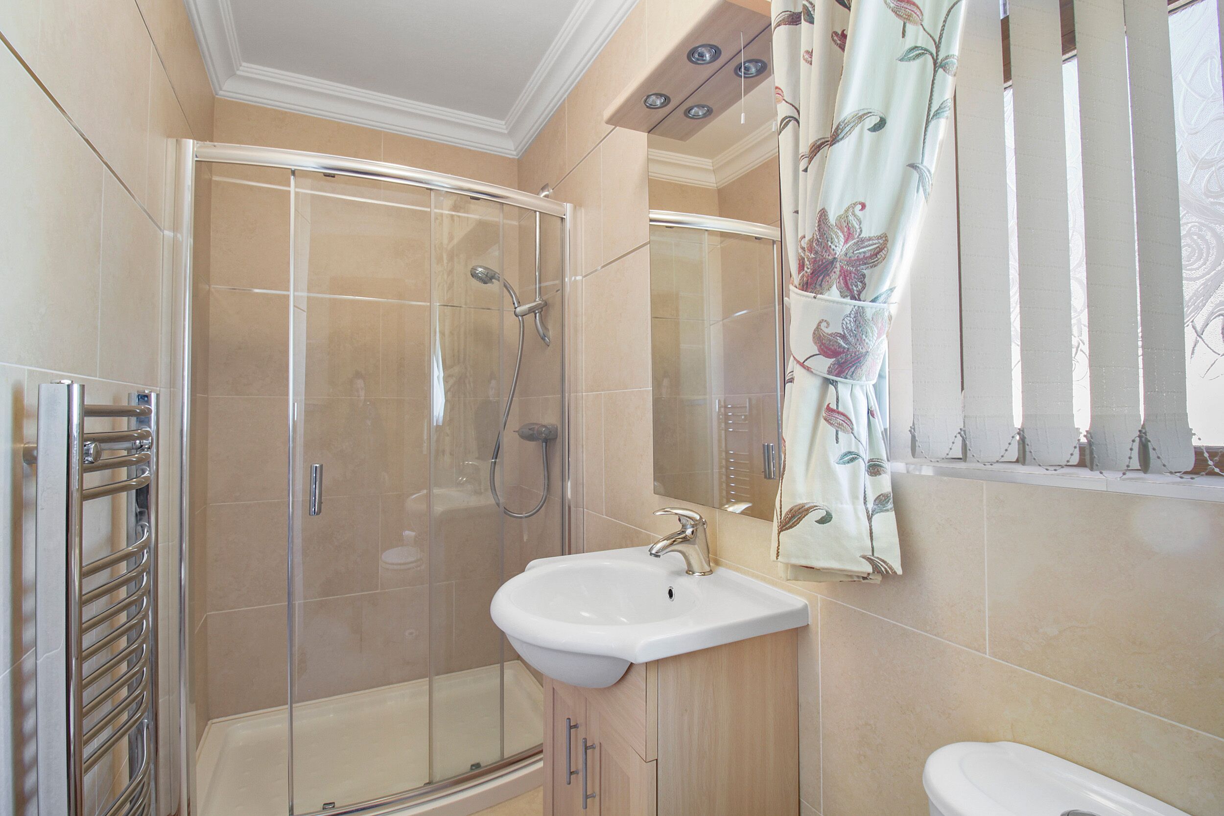 A bathroom with a glass-enclosed shower, a sink, and a toilet.