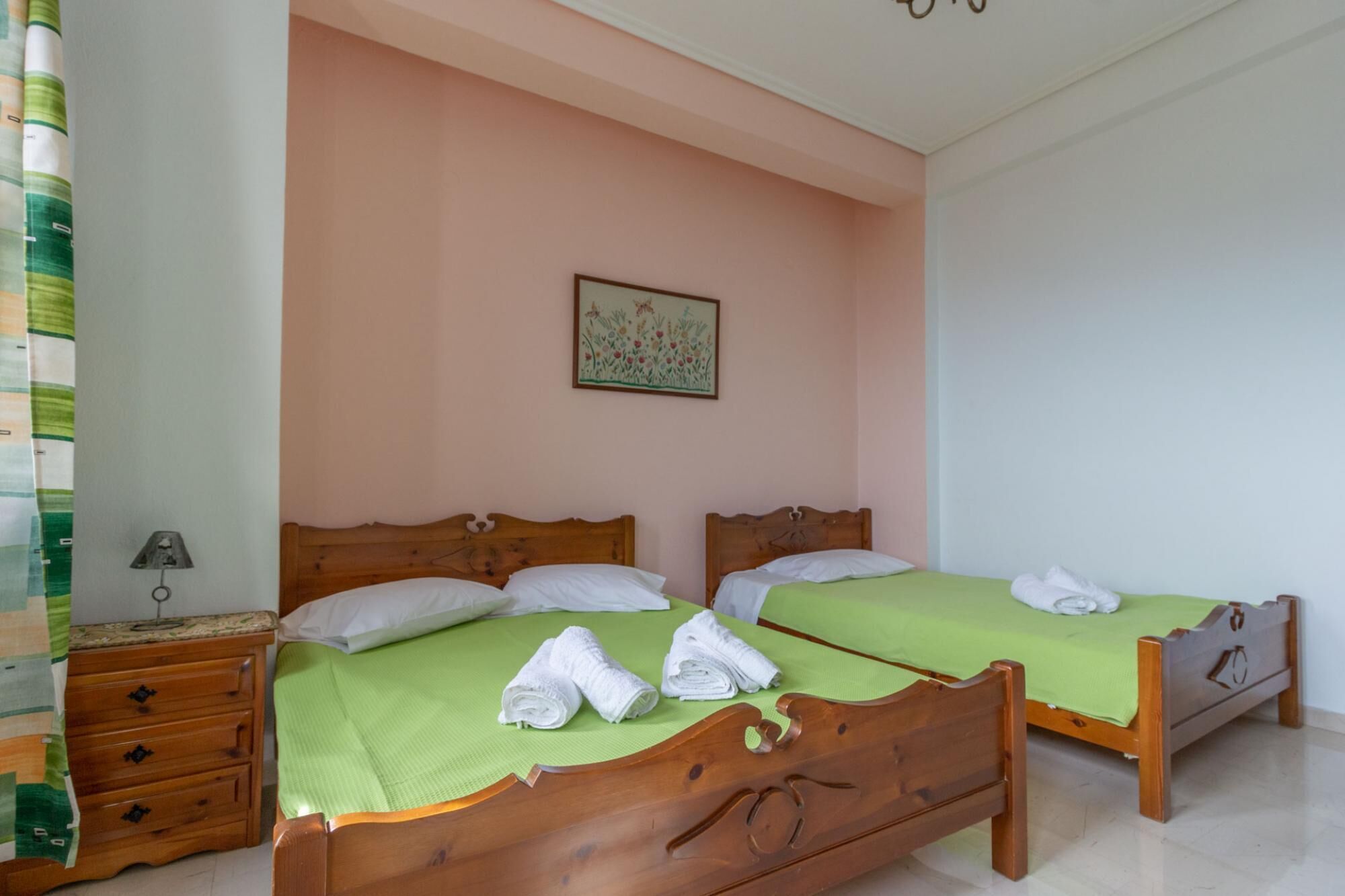Un dormitorio con dos camas de madera, sábanas verdes y toallas blancas.