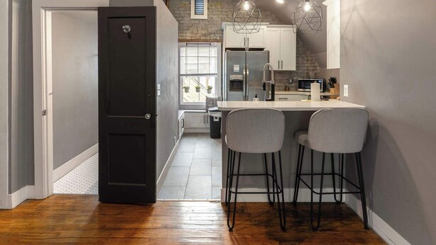Una cocina moderna con una isla central, taburetes de bar e iluminación colgante.