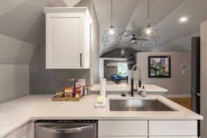 A modern kitchen with a dishwasher, a sink, and a countertop with various items.