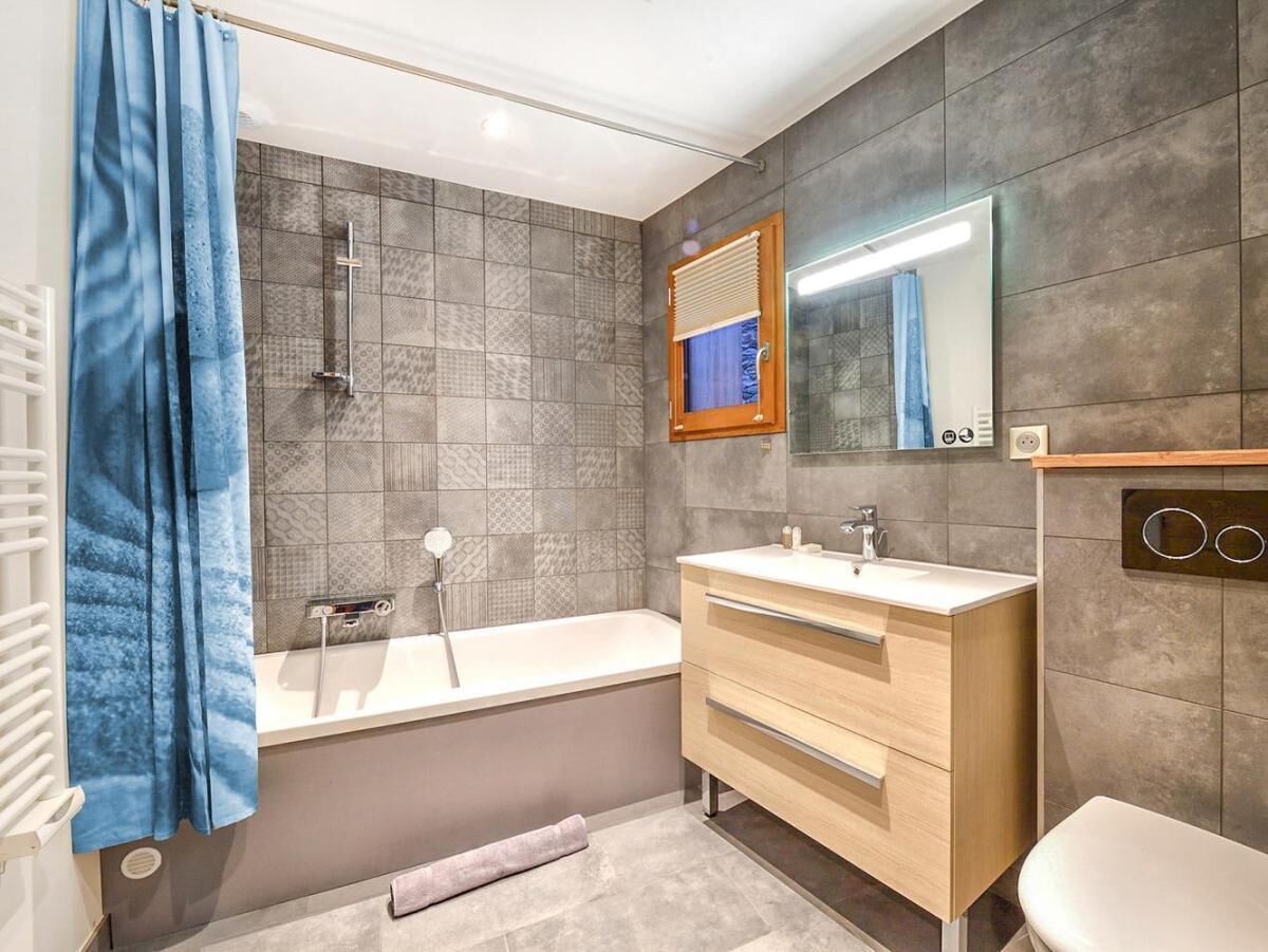 A modern bathroom with a bathtub, a vanity with a mirror, and a toilet.