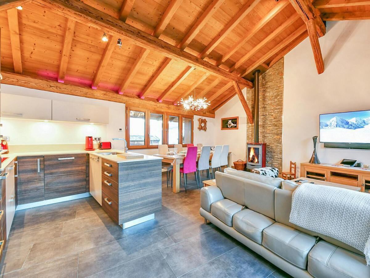 Een ruime woonkamer met een moderne keuken, een open haard en een grote televisie.