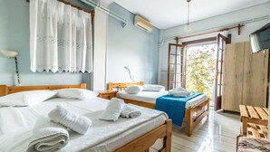 A hotel room with two wooden beds, a wooden bench, a wardrobe, and a view of the outdoors. - Villa Zina Studio 1 (Zagora-Mouresi)