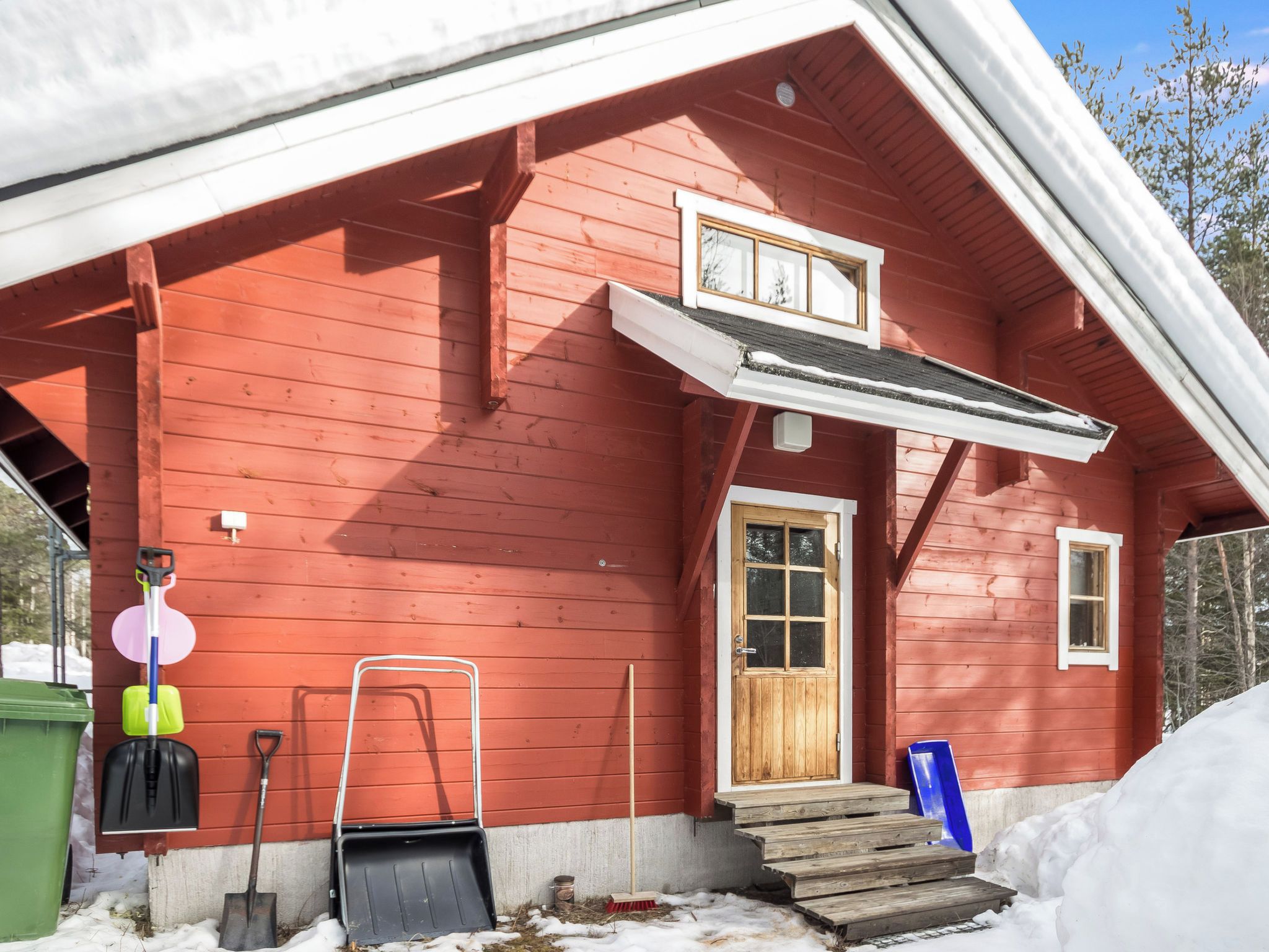 Une maison en bois rouge avec une porte d’entrée, un petit porche et des marches menant à l’entrée.