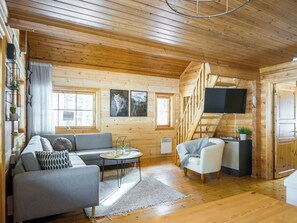 A cozy cabin interior with a sofa, armchair, and a flat-screen TV mounted on the wall. - Lähteenmaa by Interhome (Hyrynsalmi)