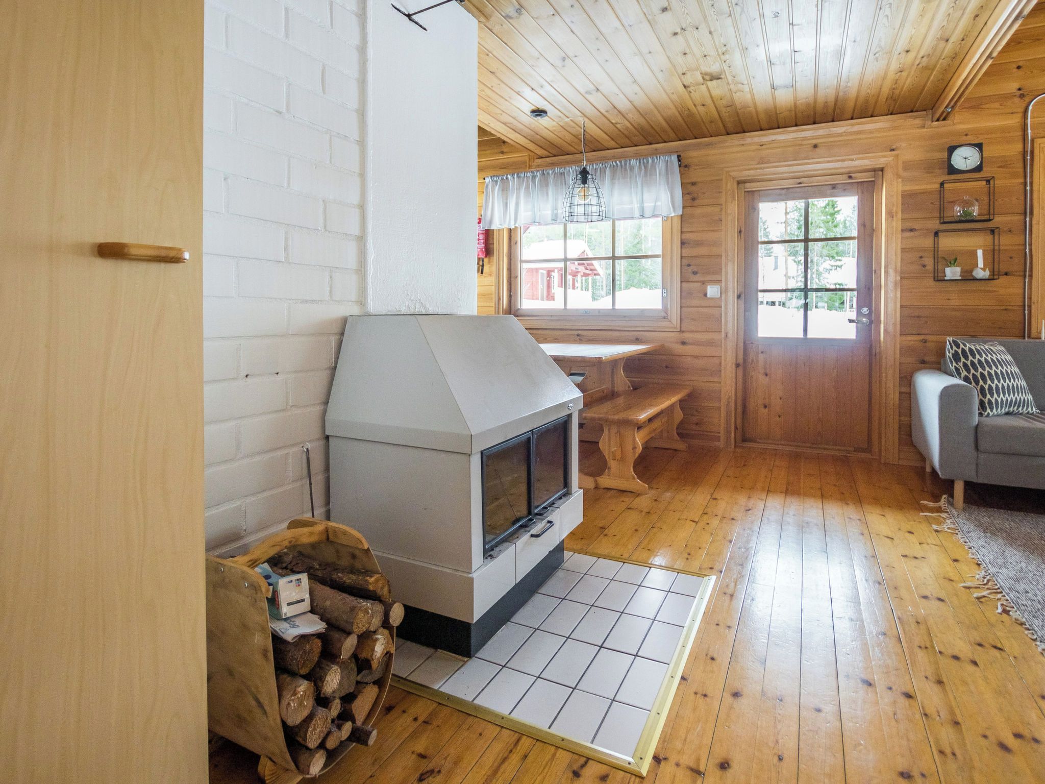 Un intérieur de chalet chaleureux avec une cheminée, des murs en bois, un coin repas et un canapé.