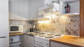 A compact kitchen with a microwave, stove, and oven.