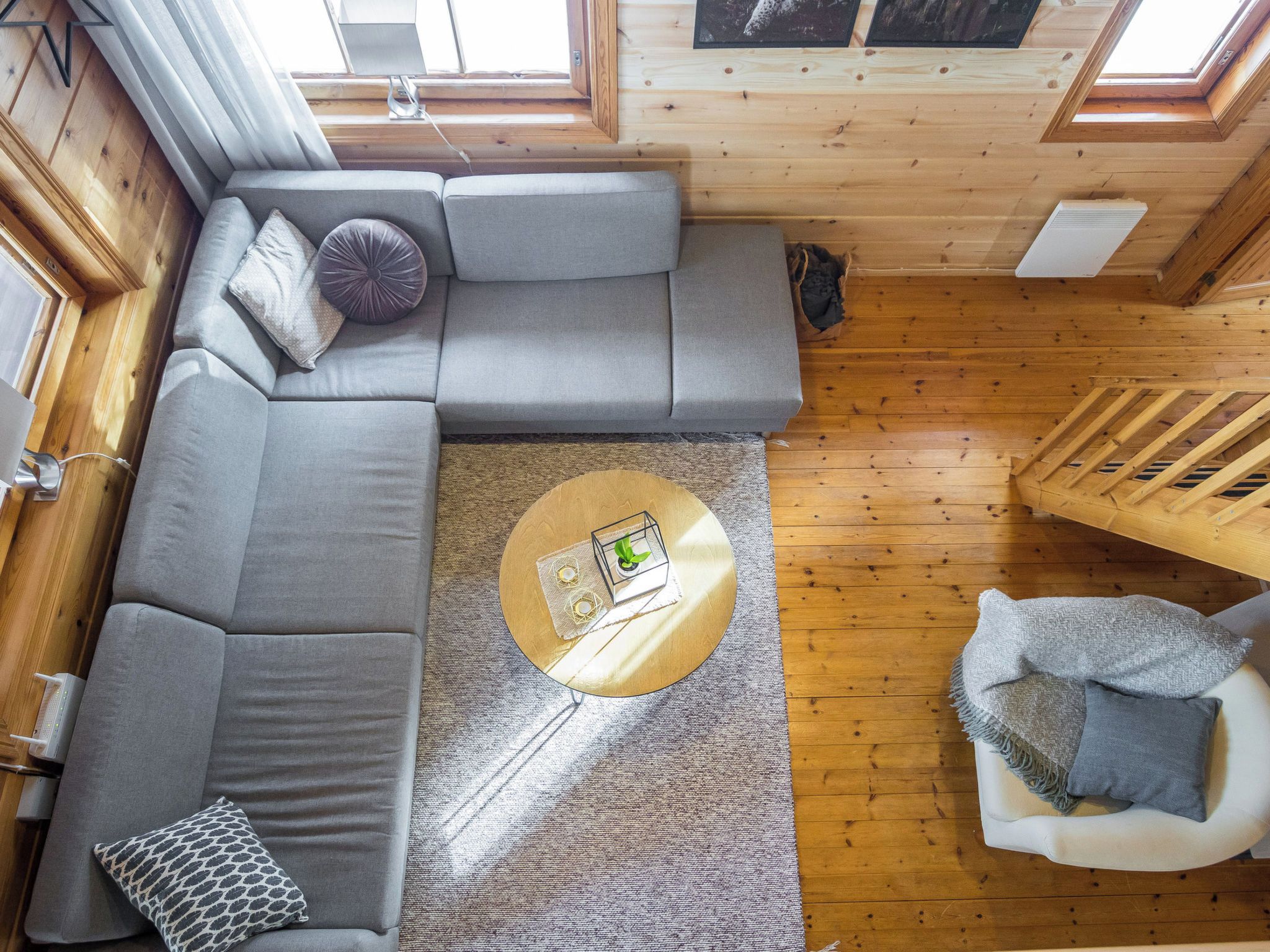 A cozy cabin interior with a sectional sofa, a round coffee table, and a small white armchair.