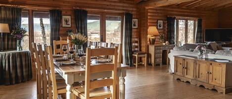 A wooden cabin interior with a dining area, kitchen, and living space.