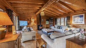A cozy log cabin interior with a fireplace, comfortable seating, and a television. - Croft Kincardine -  a lodge that sleeps 8 guests  in 4 bedrooms (Boat of Garten)