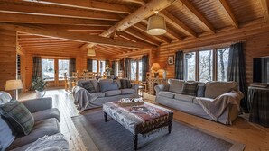 A cozy log cabin interior with two sofas, a coffee table, and a TV. - Croft Kincardine -  a lodge that sleeps 8 guests  in 4 bedrooms (Boat of Garten)