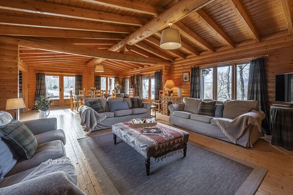 Un intérieur chaleureux de chalet en bois, avec deux canapés, une table basse et un téléviseur.