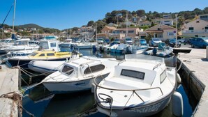 Un port de plaisance où sont amarrés plusieurs bateaux, entouré de maisons et surplombé par un ciel bleu clair.