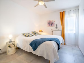 A bedroom with a bed, a nightstand, a lamp, a radiator, and a window with curtains.