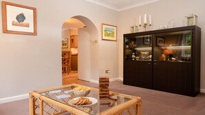 A dining area with a glass-top table, wicker chairs, a bowl of chips, and a stack of playing cards. - Four Pines Lodge -  a house that sleeps 8 guests  in 4 bedrooms (Dulnain Bridge)