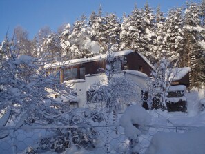 A snow-covered lodge with a wooden exterior, surrounded by trees. - Pine Ridge Lodge -  a lodge that sleeps 8 guests  in 4 bedrooms (Boat of Garten)