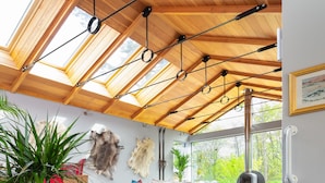 A room with a high ceiling, skylights, a fireplace, a sofa, and a staircase. - River House Garden Rooms -  a house that sleeps 2 guests  in 1 bedroom (Aviemore)