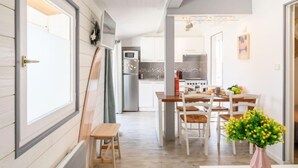 Una cocina moderna con comedor, piso de madera y una pequeña mesa con sillas.